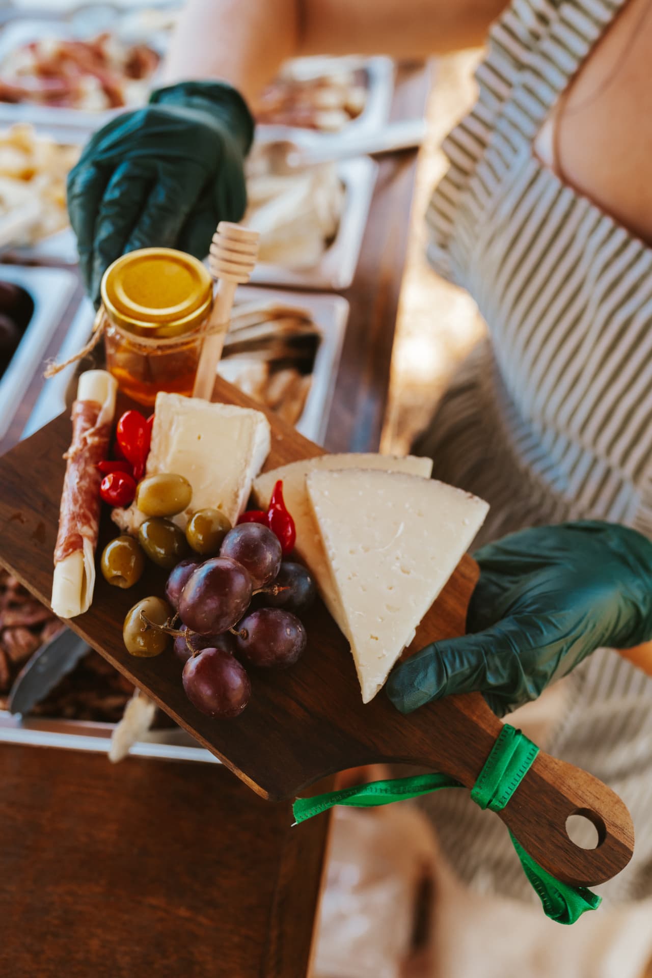 A finished charcuterie board with cheeses, meats, grapes, olives and honey