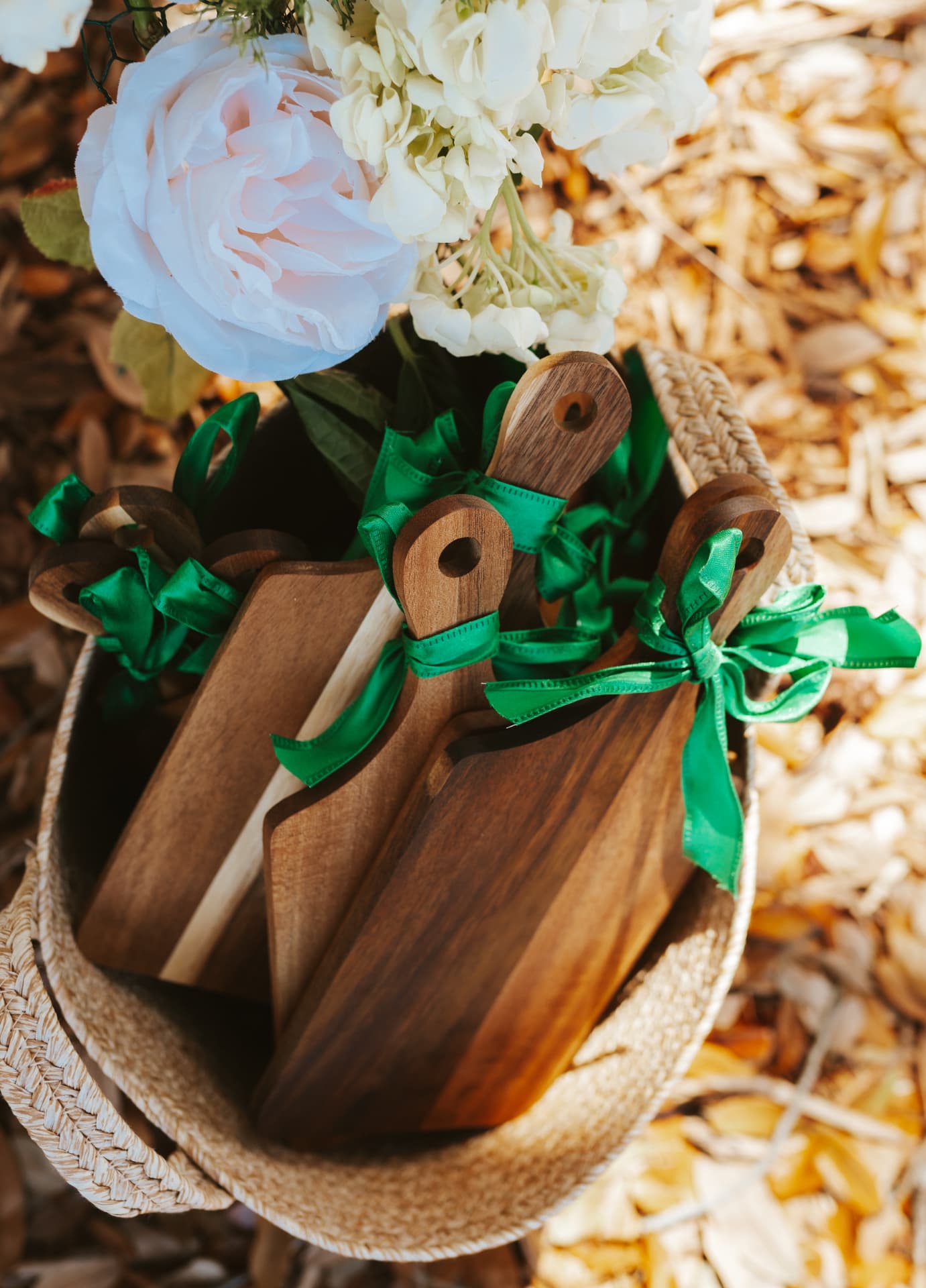 Wooden charcuterie boards tied with green ribbon beside pale flowers