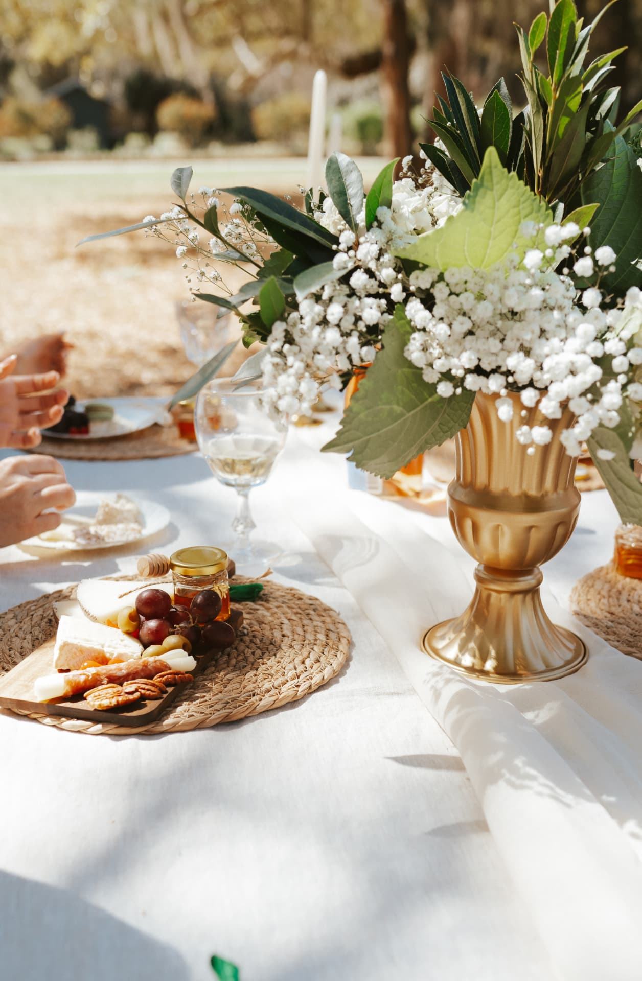 A garden table set with flowers, wine and individual charcuterie boards